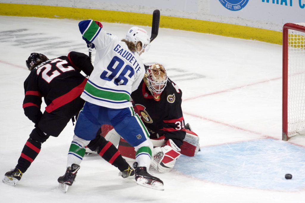 Vancouver Canucks center Adam Gaudette and Ottawa Senators goalie Joey Daccord scramble for control of the puck